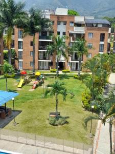 a park with a playground with palm trees and a building at Habitación dentro de un Apartamento compartido in Ibagué