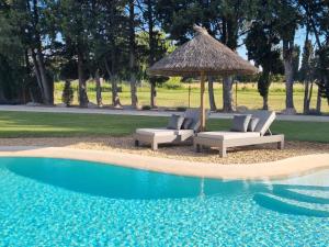 two chairs and an umbrella next to a swimming pool at Le gîte des Limites in Rognonas