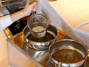 a person is pouring food into a strainer at Hotel Hillarys in Osaka