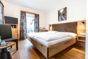 um quarto com uma cama grande e uma cadeira em Hotel-Garni Schernthaner em Sankt Gilgen