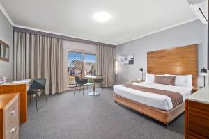 a hotel room with a bed and a desk at Quality Hotel Dickson in Canberra