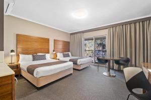 a hotel room with two beds and a table at Quality Hotel Dickson in Canberra