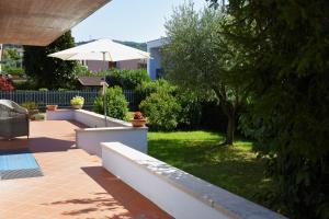 eine Terrasse mit einem Sonnenschirm und einem Garten mit Gras in der Unterkunft Canevon Suite Apartment in Bardolino