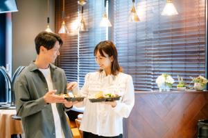 a man and a woman holding plates of food at Hotel Hillarys in Osaka