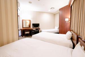 a hotel room with two beds and a desk at Hotel Hillarys in Osaka