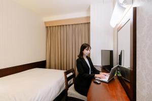 a woman sitting at a desk with a laptop at Hotel Hillarys in Osaka