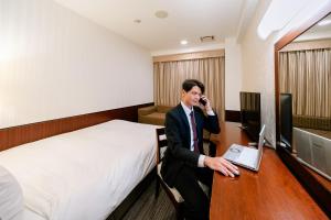 a man talking on a phone in a hotel room at Hotel Hillarys in Osaka