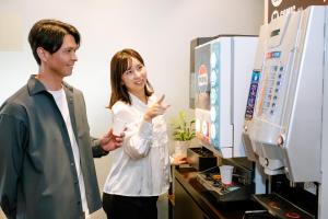 a man and a woman standing in front of a computer at Hotel Hillarys in Osaka