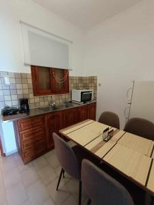 Agia ErmioniにあるNisaki chios apartmentsのキッチン(テーブル、椅子、電子レンジ付)