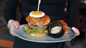 a person holding a plate with a sandwich with an egg on it at AURORA Tarnów in Tarnów