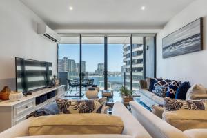 a living room with a couch and a large window at VAQUAY Glamptons In Docklands in Melbourne