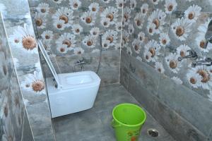een badkamer met een toilet en een groene emmer bij Hotel Harihar Atithi Bhawan in Naimishāranya