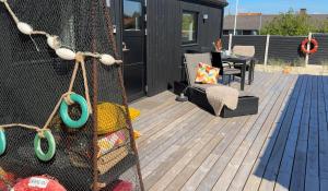 NymindegabEsehytter Luxury Holiday Home near Beach的带屏风的甲板，配有椅子和桌子