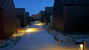 a wooden walkway with lights on it at night at Esehytter Luxury Holiday Home near Beach in Nørre Nebel