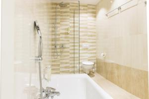 uma casa de banho com um chuveiro, uma banheira e um WC. em WH Apartments em Ljubljana
