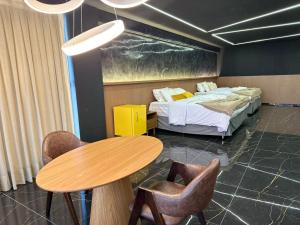a room with two beds and a table and chairs at HOTEL NOVO CENTRO in Petrolina