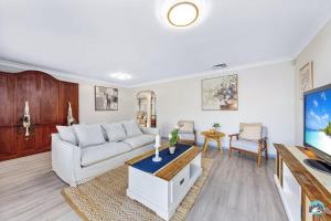 a living room with a white couch and a tv at Aircabin - Woy Woy - Water Front - 6 Beds Lux Home in Daleys Point