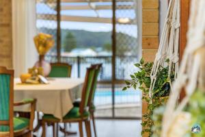 uma sala de jantar com mesa e cadeiras e uma piscina em Aircabin - Woy Woy - Water Front - 6 Beds Lux Home em Daleys Point