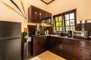 a kitchen with wooden cabinets and a microwave at PROMO Stylish Spacious 3BD Villa in Kerobokan