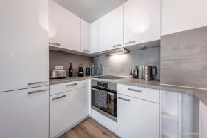 a white kitchen with white cabinets and appliances at Artdesign - 8 Pers - nähe Speyer Mannheim Heidelberg in Hockenheim