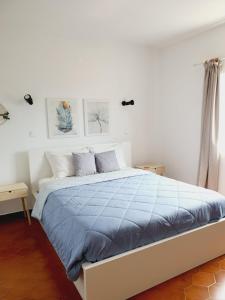 - une chambre blanche dotée d'un lit avec des draps bleus dans l'établissement Casa Olívia, à Carrapateira