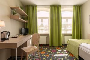 una camera d'albergo con scrivania e tende verdi di City Hotels Rūdninkai a Vilnius