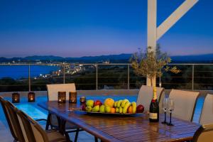 Rhodes Kallithea Villa - Zafira Private Pool Gem في كاليثيا رودس: طاولة مع وعاء من الفواكه وزجاجة من النبيذ