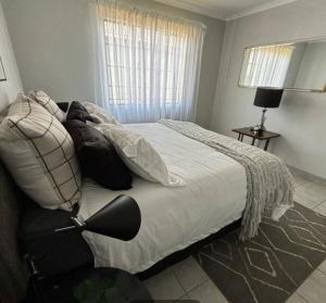 a bedroom with a large bed with white sheets and pillows at Lux Homes Property's in Johannesburg