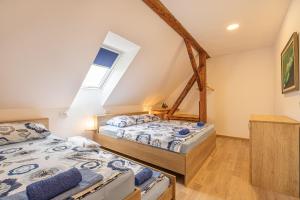 two beds in a attic bedroom with a window at Holy Harmony Suites in Velike Bloke