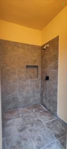 a bathroom with a shower with a stone wall at Menhir Maya in Xetna