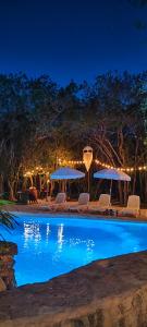 a swimming pool with chairs and umbrellas at night at Menhir Maya in Xetna