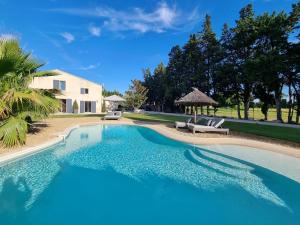 a swimming pool with two chairs and a house at Mas Paloma in Rognonas