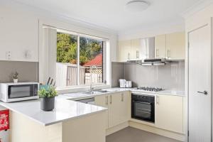 a kitchen with white appliances and a large window at Luxe Double Room in Panania - Nearby Stations & Shops - Shared Bathroom in Panania