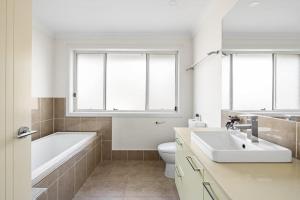 a bathroom with a tub and a toilet and a sink at Luxe Double Room in Panania - Nearby Stations & Shops - Shared Bathroom in Panania
