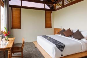 a bedroom with a large bed and a table at Anandathu Villas in Mengwi