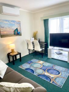 a living room with a couch and a flat screen tv at City Heart Motel Warrnambool in Warrnambool