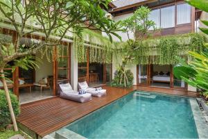 a house with a swimming pool in a garden at Anandathu Villas in Mengwi