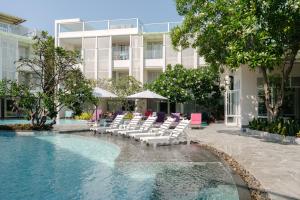 a swimming pool with lounge chairs and a building at The Sea Cret Hua Hin in Hua Hin