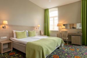 um quarto de hotel com uma cama grande com cortinas verdes em City Hotels Rūdninkai em Vilnius