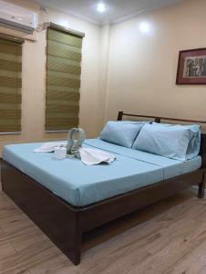 a bedroom with a bed with blue sheets and blue pillows at Marietta's Hotel in Bajuyan