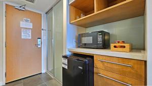 een keuken met een magnetron en een zwarte koelkast bij Ocean View Room at a resort in Honolulu