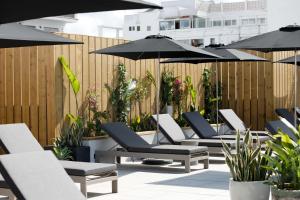 szereg leżaków i parasoli na patio w obiekcie Stic Urban Hotel & SPA w mieście San Antonio