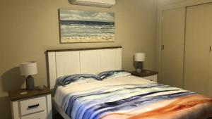 a bedroom with a bed and two night stands with lamps at Bright and Cheery Surflinks in Hawks Nest