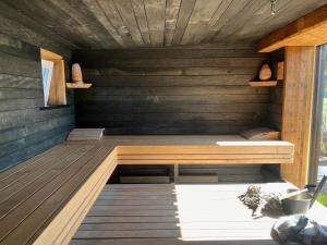 a sauna with a bench on a wooden deck at Black House- Lake garden sauna in Tīnūži
