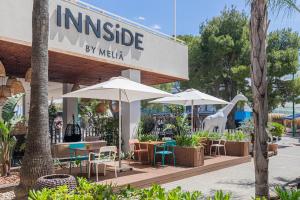 ein Restaurant mit Tischen, Stühlen und Sonnenschirmen in der Unterkunft INNSiDE by Meliá Alcudia in Port d'Alcúdia
