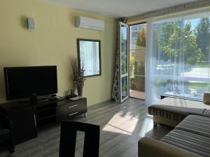 a living room with a television and a sliding glass door at Apartment with terrace in Spa Complex in Burgas City