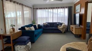 un salon avec un canapé bleu et une télévision dans l'établissement Best Family Beach Cottage!, à Hawks Nest