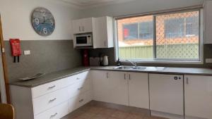 - une cuisine avec des placards blancs, un évier et une horloge dans l'établissement Best Family Beach Cottage!, à Hawks Nest 9 autres photos