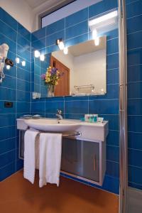 a blue tiled bathroom with a sink and a mirror at Hotel San Terenzo in Lerici