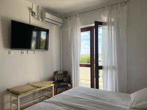 a bedroom with a bed and a tv and a window at Room Novakovic in Biograd na Moru